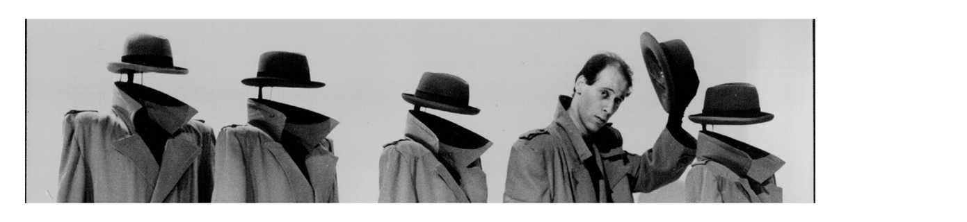 A man in a trench coat doffs his hat whilst in a row of mannequins with trench coats and hats